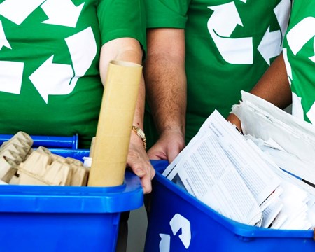 People in green shirts holding recycling receptacles