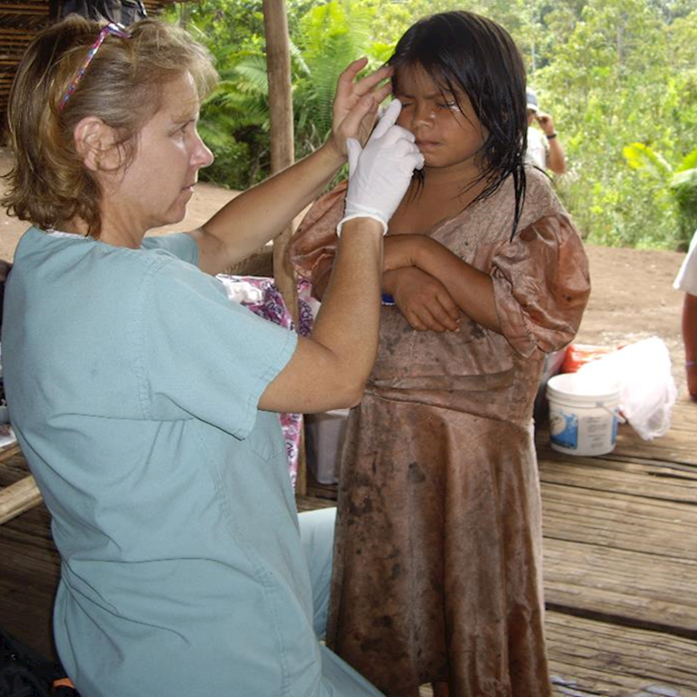 Doctor in village applying ointment to child's eyes