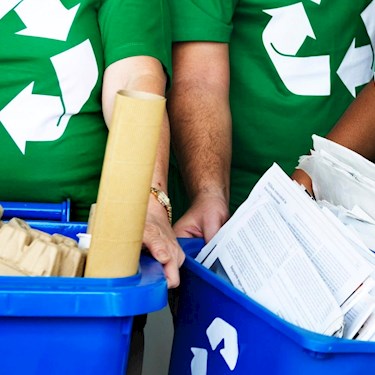 People in green shirts holding recycling receptacles